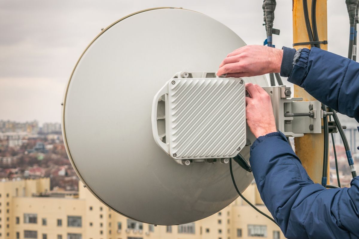 Service and repair of a powerful radio relay base station of mobile communication. There is a wireless data transmitter on the city building. Telecommunication concept.